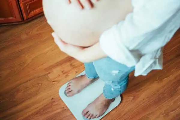 Image of woman weighing herself and experiencing weight gain through pregnancy Shefford
